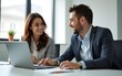 © Donna - Two business professionals engage in discussion during a meeting, using laptops and documents placed on table. Bright, modern office environment enhances collaborative work atmosphere. High quality