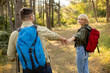 © BGStock72 - Couple enjoys a hike in a sunlit forest while holding hands and smiling at each other