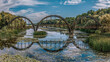 © Tibor.photo.Holczer - Arched wooden pedestrian bridge over a lake. Harmony of nature and architecture, unique scenery among aquatic plants.