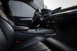 © Aerial Film Studio - Close up of BMW X6 interior showing black leather seats, sleek center console, gear shifter, and modern dashboard with digital display in soft lighting.