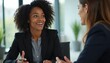 © Raisa - Pro woman in business attire engages in conversation with colleague in a modern office setting. Both women, dressed in suits, share expressions of attentiveness and engagement during their discussion.