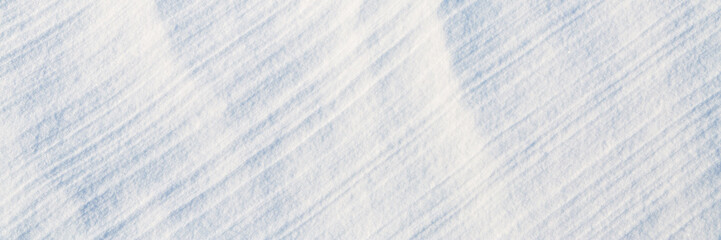 Wall Mural - Beautiful winter background with snowy ground. Natural snow texture. Wind sculpted patterns on snow surface. Wide panoramic texture for background and design.