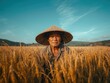 © Palmesrk - A farmer in a straw hat stands confidently among golden rice stalks under a clear blue sky