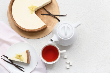 Wall Mural - Cut sweet cheesecake with vanilla flowers and cup of tea on white background