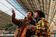 © bernardbodo - Tourists using smart phone and pointing inside station building