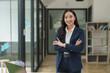 © Phimwilai - Young asian businesswoman smiling with arms crossed in modern office