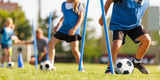 School boy dribbling soccer ball in slalom training drill. Football training camp for school kids. Soccer practice equipment on grass pitch