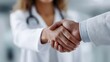 © Bussakon - Two medical professionals in white coats shaking hands symbolizing trust and partnership in healthcare