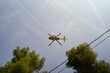 © Connect Images - Helicopter flying overhead with trees and power lines in the foreground against a blue sky. Marseille, France