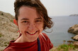 © Connect Images - Smiling woman with short hair by rocky seaside under clear sky. Marseille, France