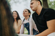© qunica.com - A group of friends relaxes in an outdoor park setting, enjoying each other's company.