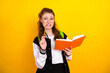 © deagreez - Charming Young student thinking while holding notebook against vibrant yellow background