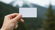 © Hendra - Hand Holding Blank White Business Card with Soft Natural Background for Branding and Design Presentation