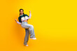 © deagreez - Cheerful young woman in trendy casual outfit posing with excitement on vibrant yellow background showcasing her youthful spirit