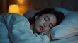 © Liera - A serene young Asian woman peacefully sleeping on her bed, surrounded by soft pillows and warm lighting.