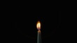 © stockbusters - Tiny candle staying black background in stillness. Wax taper burning on dark
