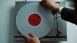 © stockbusters - Hands putting vinyl disc at vintage gramophone placed on table closeup top view