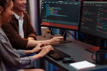 IT developers discussing with point to intelligent website development coder system running data online two screens information technology at neon light room at modern office. Infobahn.