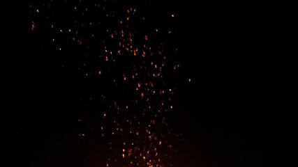 Sticker - a slow-motion shot captures sparkling fire embers floating upwards against a pitch-black background 