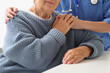 © Pixel-Shot - Nurse with senior woman holding hands at table, closeup