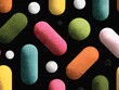 ©  Sheton - 다채로운 색상의 캡슐과 구슬이 검은 배경에 무작위로 배열된 추상적인 패턴