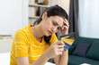 © Ratirat - Frustrated Asian woman holding multiple credit cards, showing stress from debt, overspending, or financial problems, representing money management and personal finance crisis.