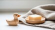 © Kamal - Wooden duck figurine with soap on a linen cloth, showcasing sustainable decor, eco-friendly personal care, and a gentle aesthetic in an environmentally conscious setting.