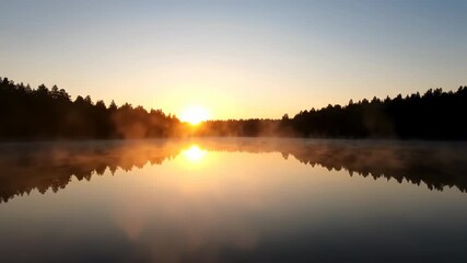 Wall Mural - The sun slowly rises over a calm lake, illuminating the misty surface and distant forest line water, light, illumination