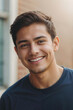 © polack - Face of happy young guy student in blue t-shirt on blurred background of high school building on sunny day and looking at camera