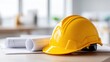 © Denis Tuev - Yellow hard hat rests on a wooden table beside rolled blueprints, showcasing construction planning and safety equipment in a bright workspace environment