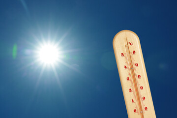 Wall Mural - thermometer showing high temperature against sky with bright sun. extremely hot weather