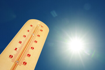 Wall Mural - thermometer showing high temperature against sky with bright sun. extremely hot weather