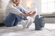 © New Africa - Young woman near electric heater on floor at home, closeup