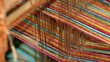 © onyengradar - Colorful threads stretch tautly across a wooden loom in a textile workshop, showcasing the intricate process of weaving with vibrant hues and textures.