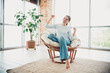 © deagreez - Charming woman seated on a cozy chair in a modern home interior enjoying a cheerful moment with natural daylight ambiance