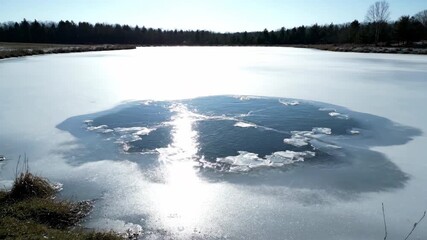 Wall Mural - Stunning timelapse capturing the slow melting of ice on a frozen pond, revealing shimmering water beneath solid, season, frozen