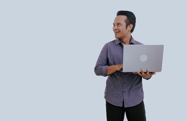 Asian man using laptop computer for business work application. Smiling handsome young man holding digital device looking aside, isolated on white background, copy space.