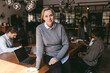 © Maskot - Portrait of smiling senior female business expert sitting on table in office