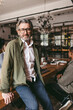 © Maskot - Portrait of smiling senior male business expert wearing eyeglasses sitting on table in office
