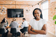© Maskot - Portrait of smiling young female business professional standing with arms crossed in office