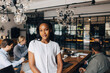 © Maskot - Portrait of confident young businesswoman standing near table in office