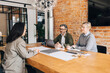 © Maskot - Male and female human resource expert taking interview of woman while sitting at table in office