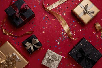 Wall Mural - Colorful gift boxes and confetti scattered on a vibrant red surface during a major sale event