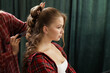 © st.kolesnikov - Stylist crafting a curly updo in salon, side profile of client during professional hairstyling