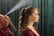 © st.kolesnikov - Stylist spraying hairspray to set curls on client in salon