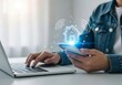 © Muddasar - A young adult male using a smartphone while working on a laptop, showcasing smart home technology.