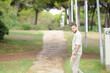 © Masakazu Tokashiki - A man is walking down a path in a park. He is wearing a tan shirt and khaki pants