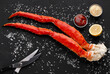 © Prostock-studio - Gourmet seafood. Cooked king crab legs served with eating tools and sauces on black salted table, top view