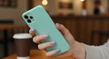 Hand holding mint green phone case with purple nails and coffee cup image