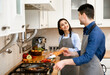 © Prostock-studio - Cooking With Family. Happy couple preparing dinner together, frying and chopping vegetables, looking at each other